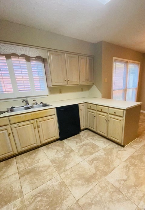A kitchen with tan cabinets and a black counter.
