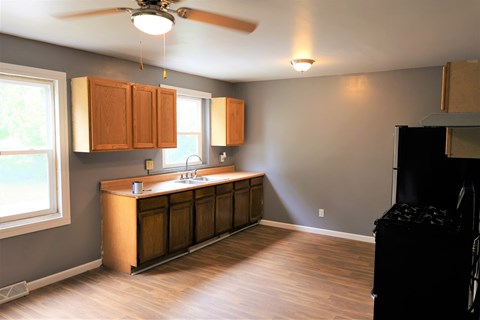 A kitchen with wooden cabinets and a ceiling fan.