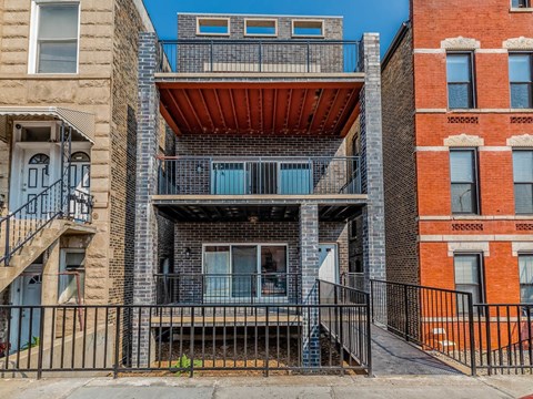 A multi-story building with a balcony and a black railing.