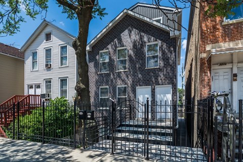 A black iron gate blocks the entrance to a brick house.