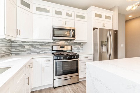A modern kitchen with white cabinets and stainless steel appliances.
