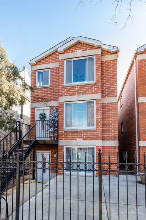 A red brick house with a black gate in front.