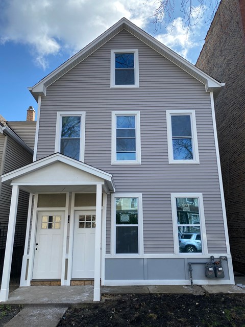 A grey house with a white door and windows.