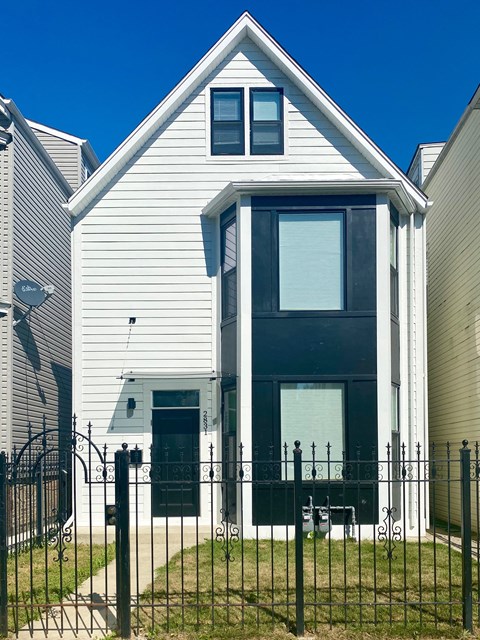 A white house with a black door and a black fence.