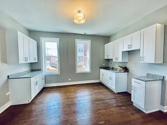A kitchen with white cabinets and a granite countertop.