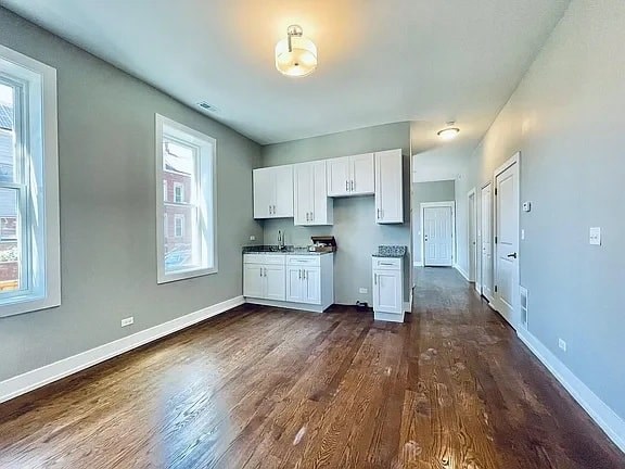 A kitchen with white cabinets and a wooden floor.