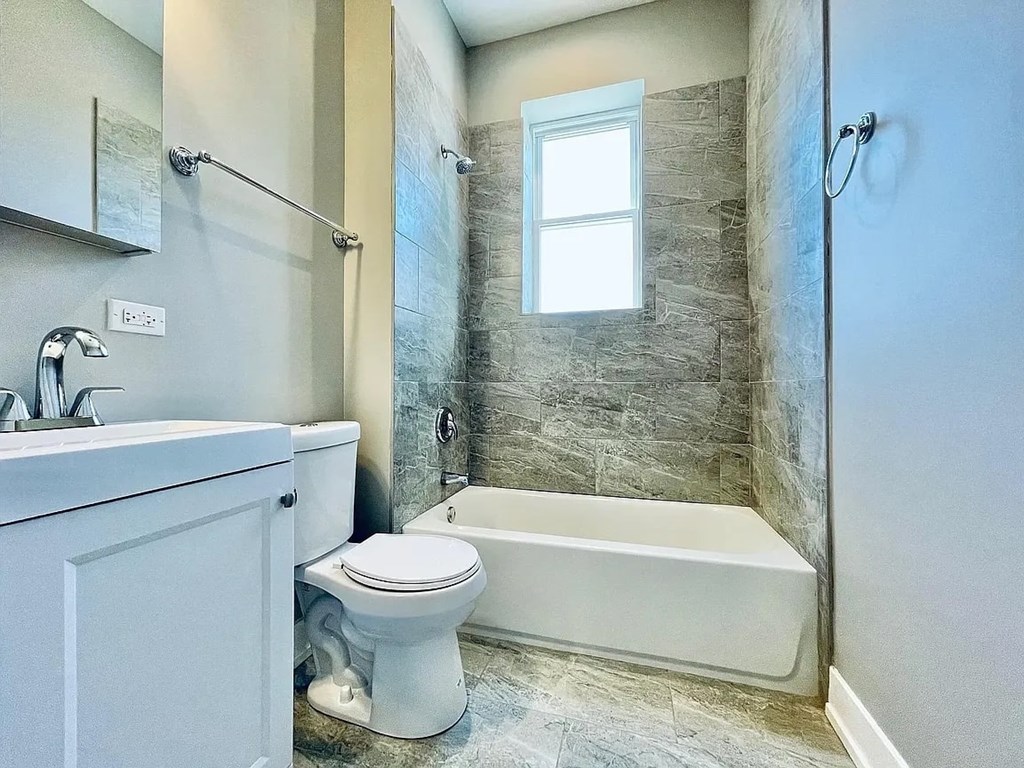 A white toilet sits next to a bathtub in a bathroom.