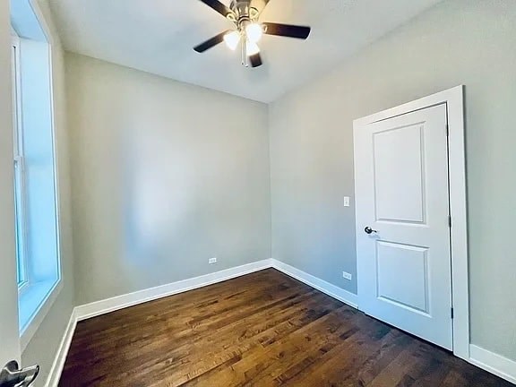 A room with a white door and a ceiling fan.