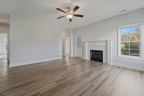 A spacious living room with a fireplace and a ceiling fan.