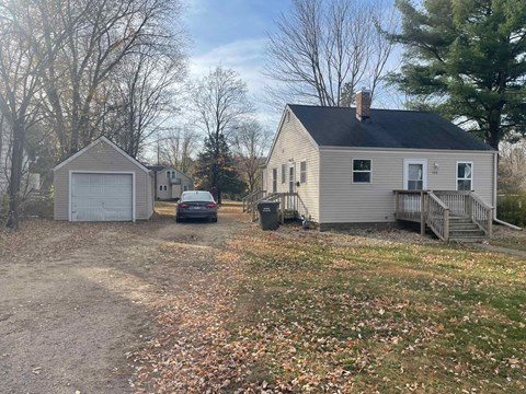 A house with a garage and a car parked in front.