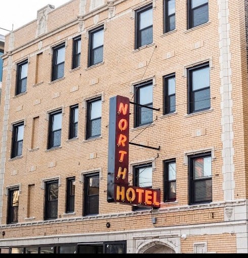 A hotel sign is hanging on a building.