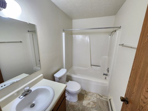 A white bathroom with a toilet, sink, and bathtub.
