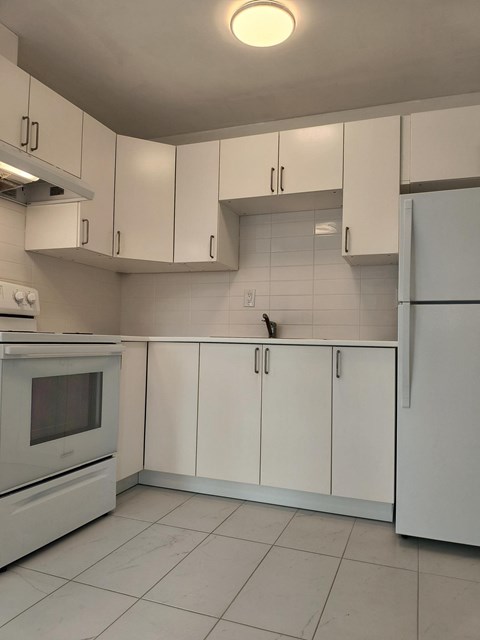 A kitchen with white cabinets and appliances.