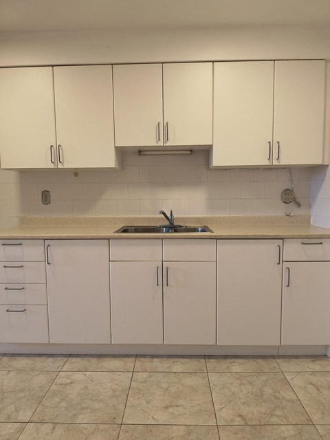 A kitchen with white cabinets and a sink.