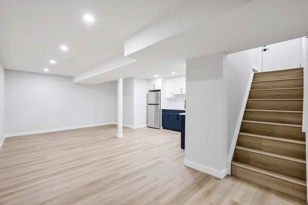A spacious room with wooden flooring and a staircase leading to another level.