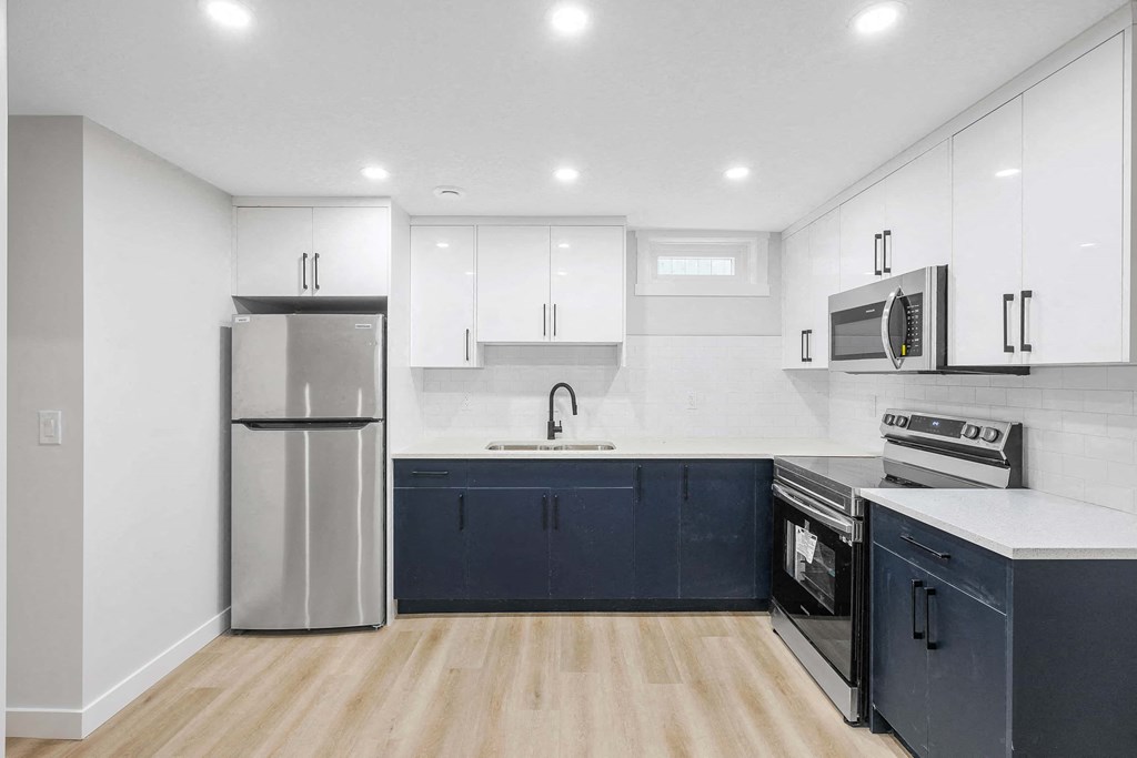 A modern kitchen with dark blue cabinets and stainless steel appliances.