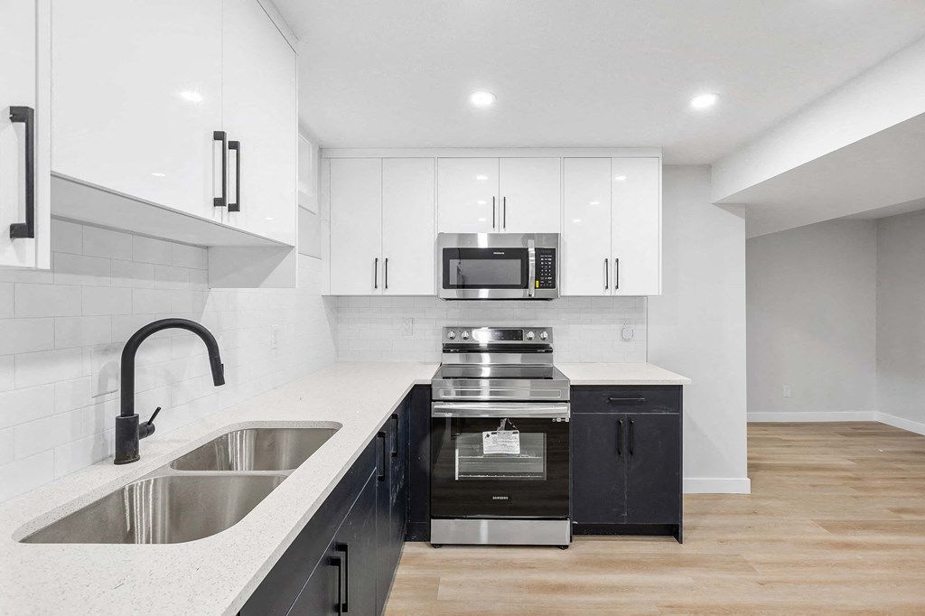 A modern kitchen with a stainless steel sink and black cabinets.