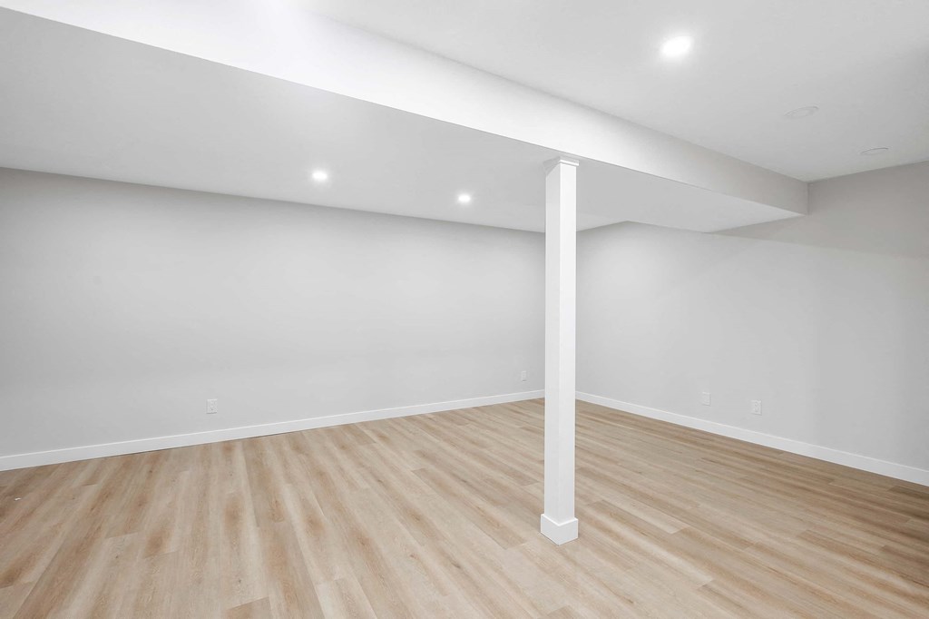A room with a white column and wooden flooring.