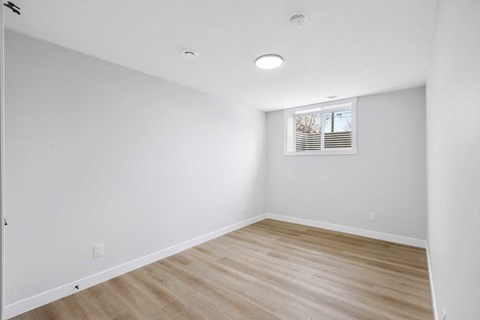 A room with wooden flooring and a window with blinds.