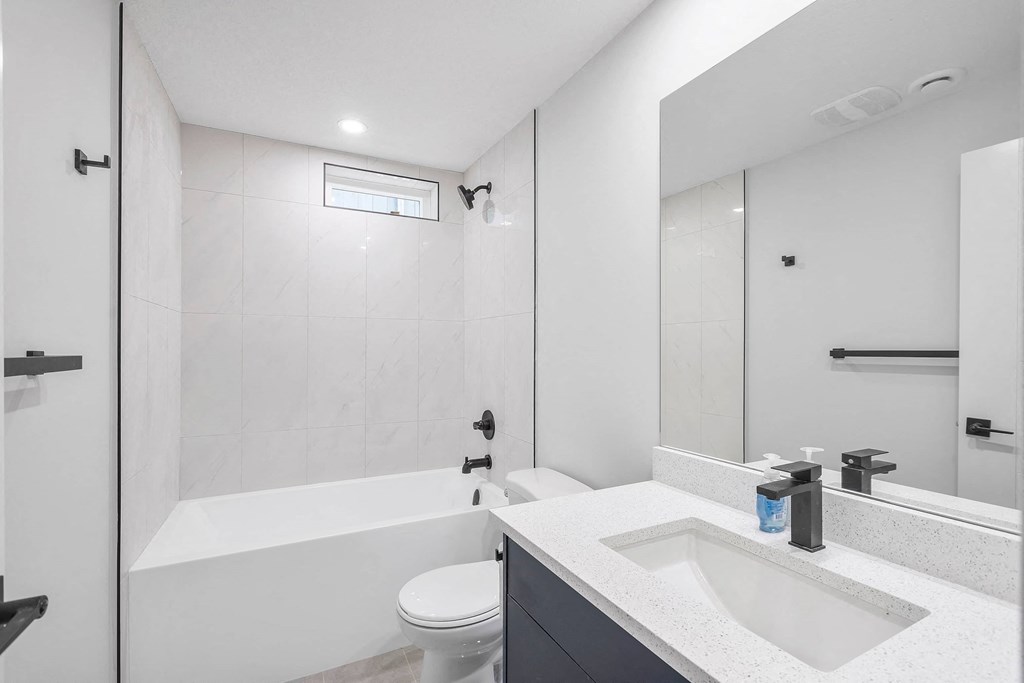 A white bathroom with a toilet, sink, and bathtub.