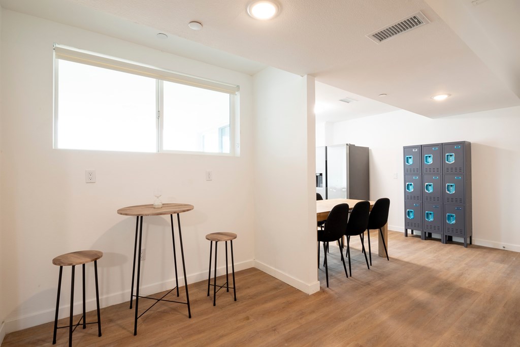 A kitchen area with a table, chairs, and a refrigerator.
