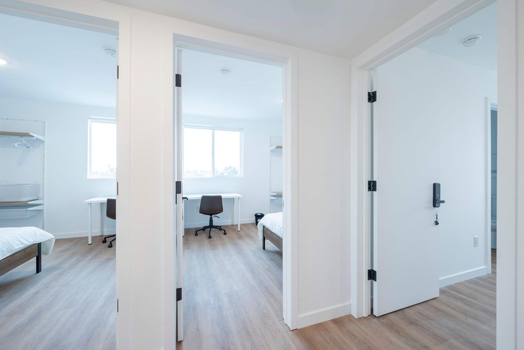 A white room with a bed, desk, and chair.