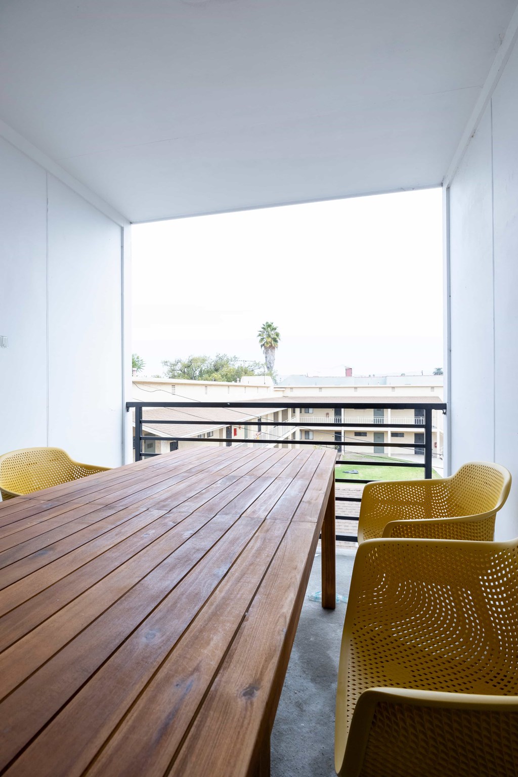 A long wooden table is surrounded by yellow chairs.