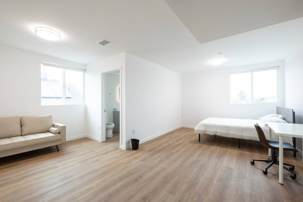 A bedroom with a bed, desk, and chair.