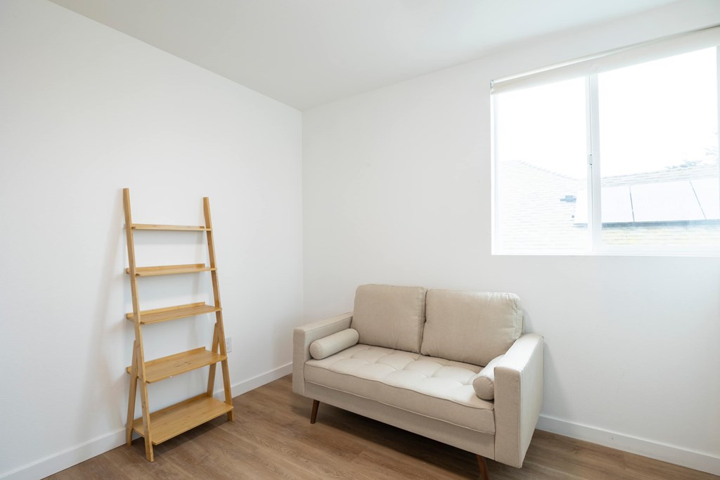 A tan couch sits in a white room with a wooden ladder to its left.