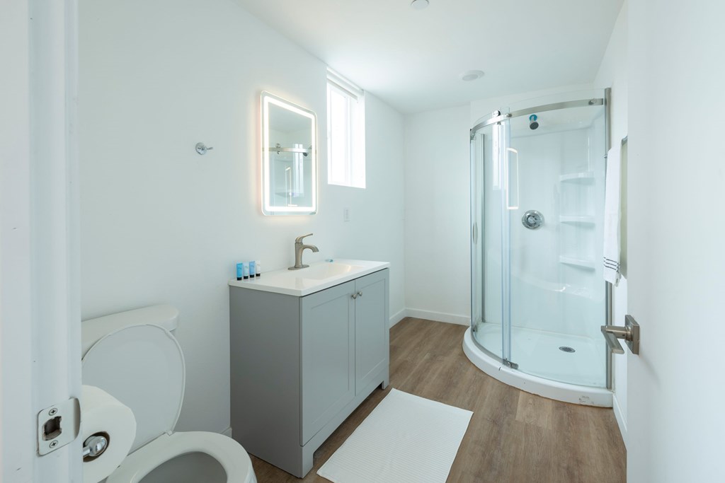 A white bathroom with a toilet, sink, and shower.