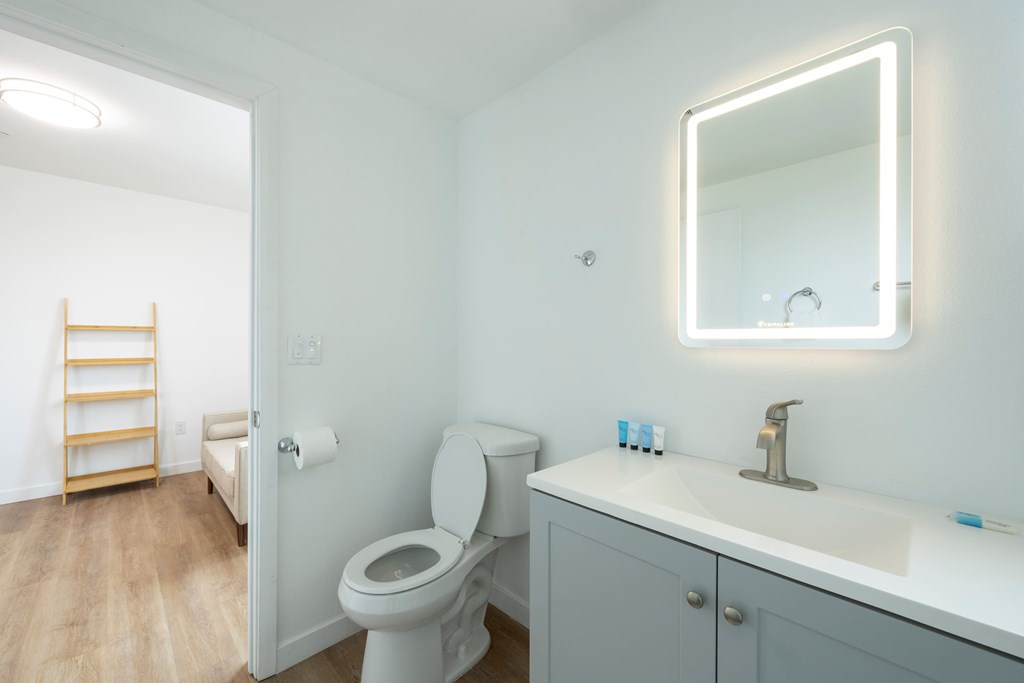 A white bathroom with a toilet, sink, and mirror.