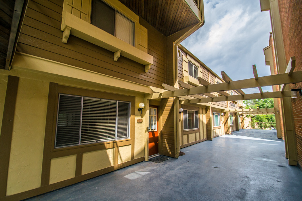 A long hallway with a yellow building on the left and a brown building on the right.