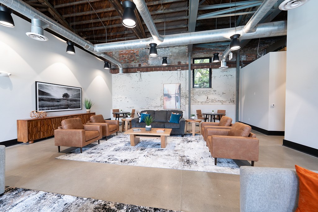 A large room with a white brick wall and a long wooden table with chairs around it.