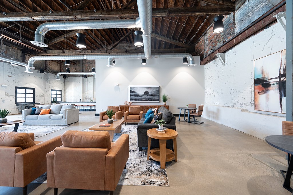 A room with a lot of brown furniture and a white wall with a painting on it.