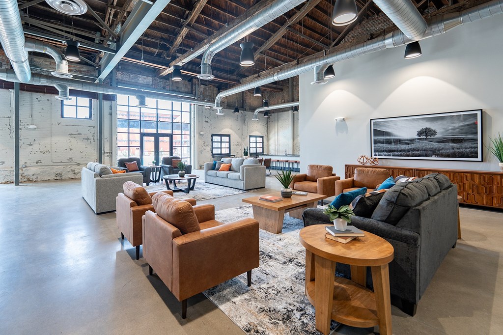 A living room with a black couch and brown chairs.