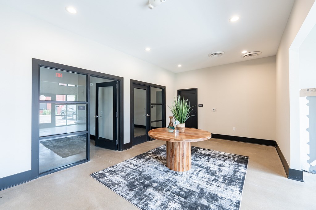 A modern living room with a wooden coffee table and a black and white rug.