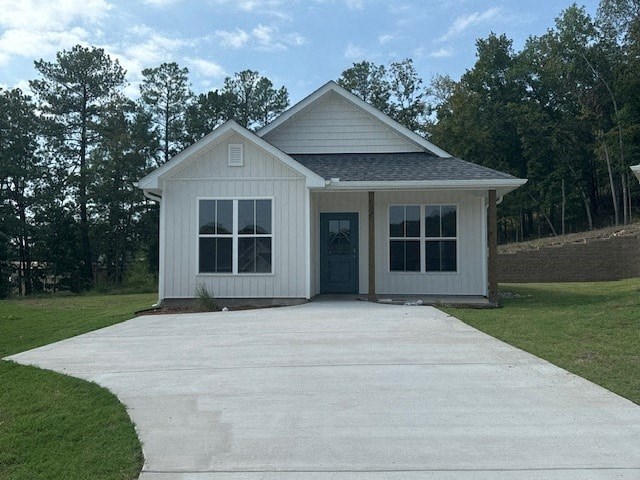 A small white house with a grey roof and a grey concrete walkway in front.
