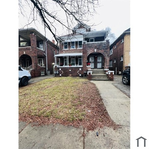 A brick house with a front yard covered in leaves.