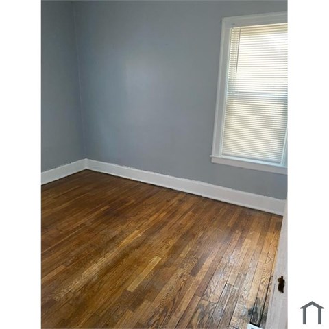 A room with wooden flooring and a window with blinds.