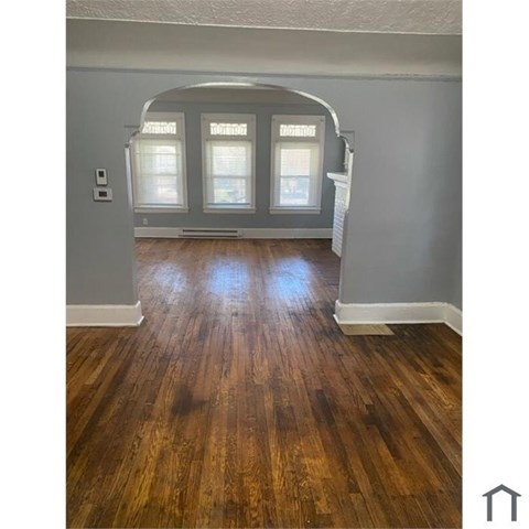 A room with wooden floors and a white archway.