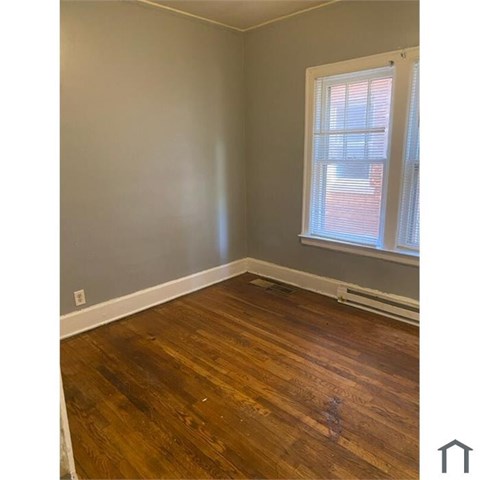 A room with wooden flooring and a window with blinds.