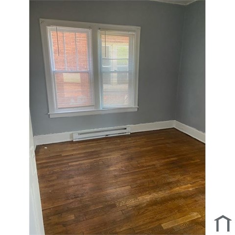 A room with a window and wooden flooring.