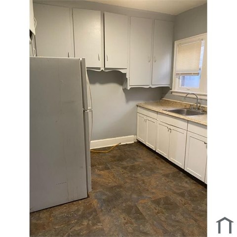 A kitchen with a white refrigerator and cabinets.