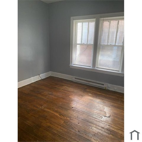 A room with wooden flooring and a window with blinds.