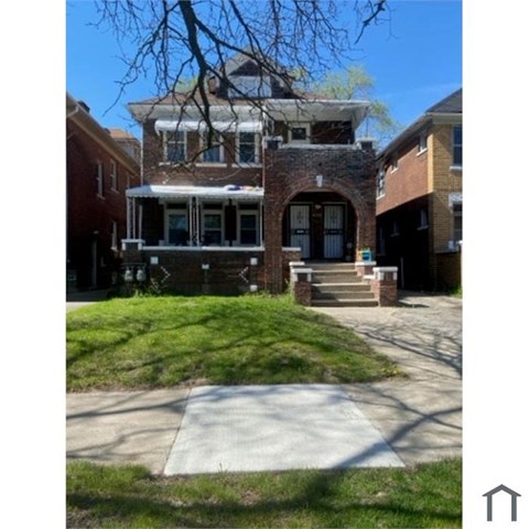 A brick house with a porch and a covered staircase leading to the front door.
