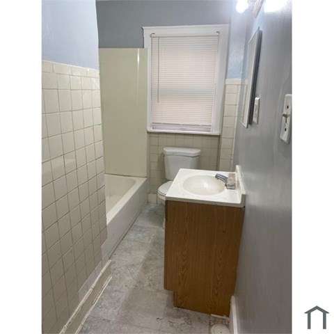 A bathroom with a sink, toilet, and a window.