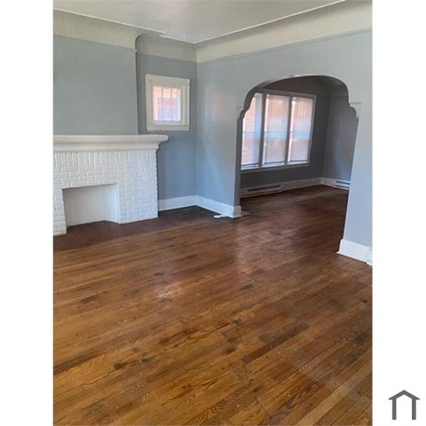 A room with a fireplace and wood flooring.