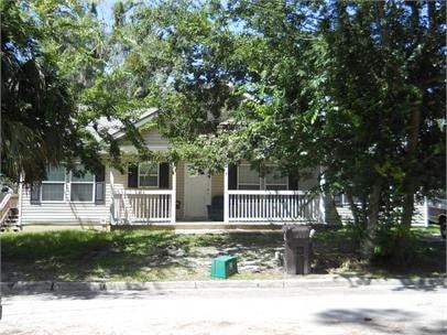 A house with a porch and a tree in front.