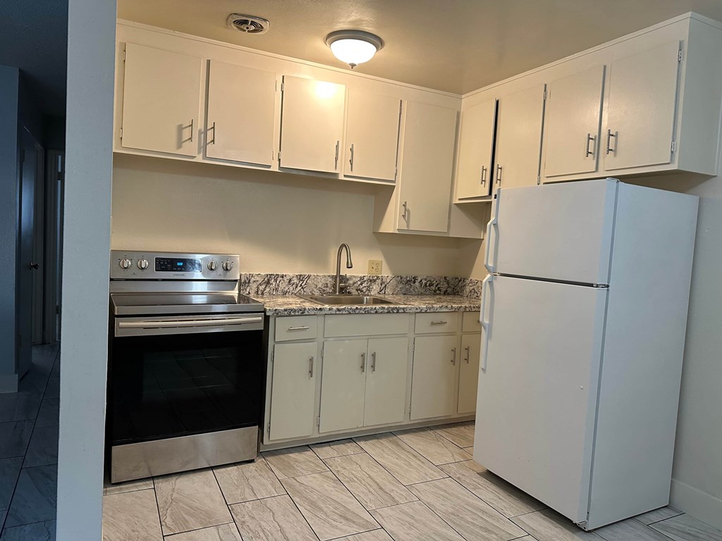 A kitchen with white cabinets and a marble countertop.