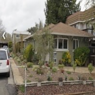 A white car is parked in a driveway.